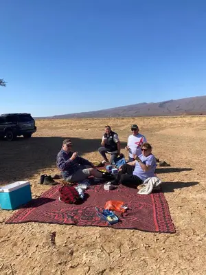 a group of people sitting on a blanket in the desert at Desert Family Camp in El Gouera