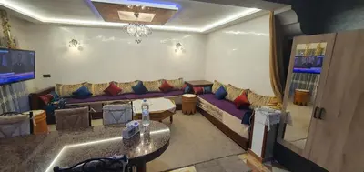 a living room with a couch and a table at Appartement tout confort sur la corniche à proximité plage in Oulad Akkou