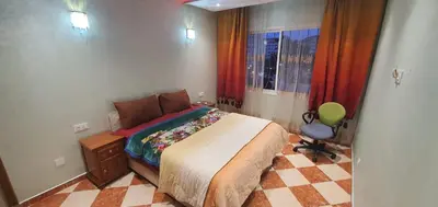 a bedroom with a bed and a chair and a window at Appartement tout confort sur la corniche à proximité plage in Oulad Akkou