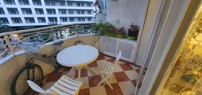 a balcony with a bike and a table and chairs at Appartement tout confort sur la corniche à proximité plage in Oulad Akkou