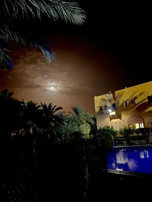 a view of a building at night with the moon at Riad Ksar Assalassil Erfoud in Erfoud