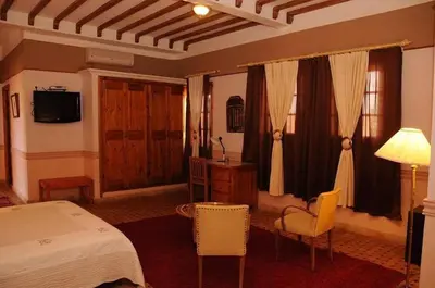 a bedroom with a bed and a desk and a television at Riad Ksar Assalassil Erfoud in Erfoud