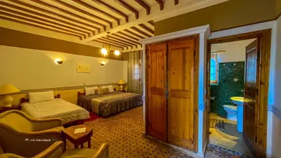a hotel room with two beds and a couch at Riad Ksar Assalassil Erfoud in Erfoud