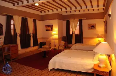 a hotel room with two beds and a table at Riad Ksar Assalassil Erfoud in Erfoud