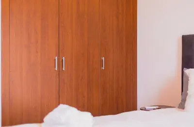 a wooden cabinet in a bedroom next to a bed at Luxury Apartment Prestigia Champ Cours Garden View in Fès