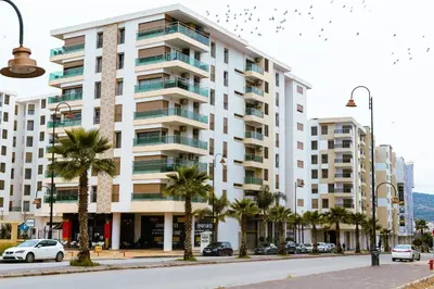 a large white building with palm trees in front of it at Luxury Apartment Prestigia Champ Cours Garden View in Fès