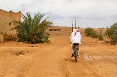 a man riding a bike down a dirt road at La Casa De GanGa in Khamliya