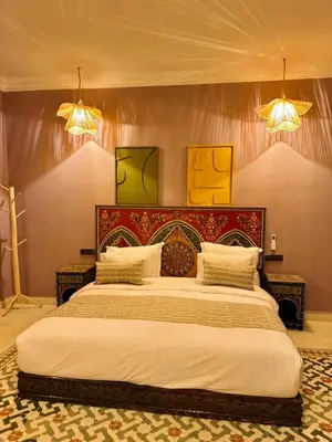 a large bed in a bedroom with two lights at riad tighmart in Merzouga