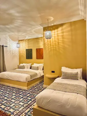 two beds in a room with yellow walls at riad tighmart in Merzouga