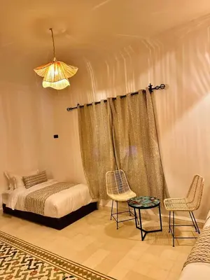 a bedroom with a bed and two chairs and a table at riad tighmart in Merzouga