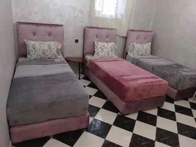 two beds in a room with a checkered floor at casa medina sanaa in Oulad Akkou