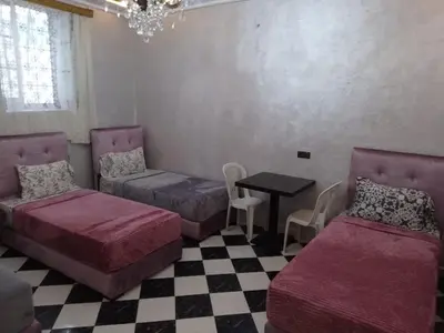 a room with two beds and a table and chairs at casa medina sanaa in Oulad Akkou