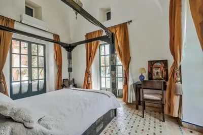 a bedroom with a bed and a desk and windows at Villa l'Aziza in Najem