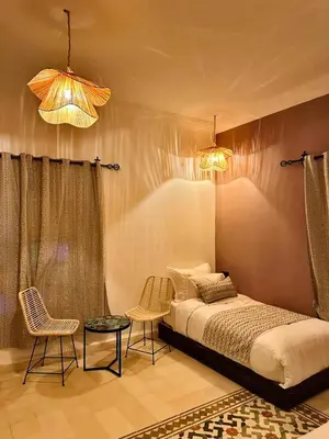 a bedroom with a bed and two chairs and two lights at riad tighmart in Merzouga