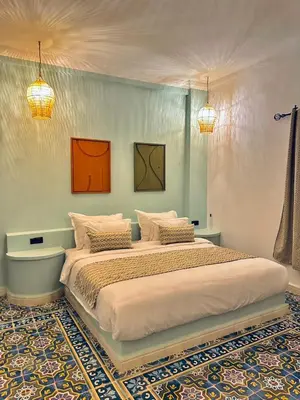 a bedroom with a large bed with two pictures on the wall at riad tighmart in Merzouga