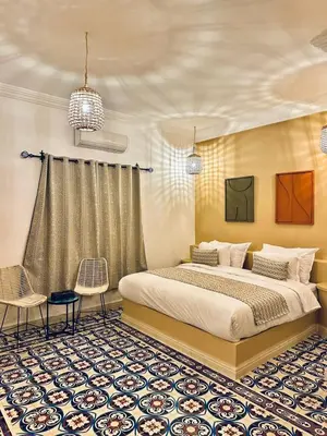 a bedroom with a large bed and two chairs at riad tighmart in Merzouga