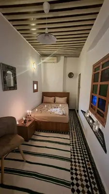 a bedroom with a bed and a chair and a table at Dar Boueden - lala hadhoum- Guest House in Fès