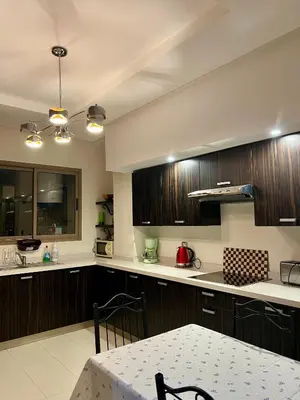 a kitchen with wooden cabinets and a table with a dining room at Moderne et spacieux appartement avec une belle vue - Espace Rihab centre ville in Fès