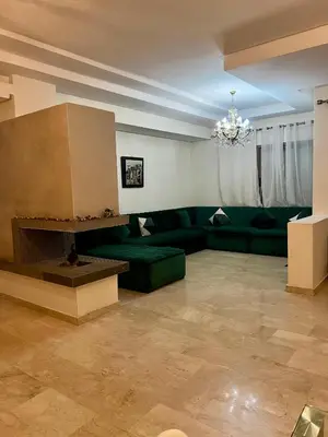 a living room with a green couch and a chandelier at Moderne et spacieux appartement avec une belle vue - Espace Rihab centre ville in Fès