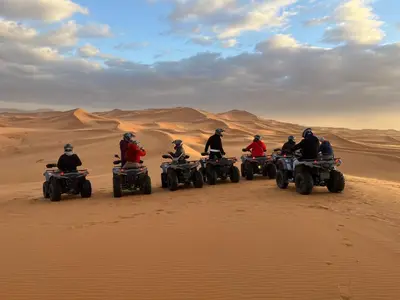 a group of people riding atvs in the desert at Merzouga ousaadi camp in Merzouga