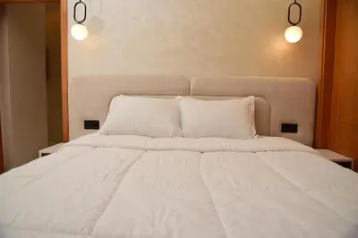 a large bed with white sheets and pillows at Stylish & Cozy Apartment with Modern Design in Beni Mellal