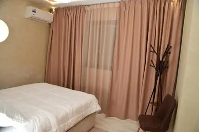 a bedroom with a bed and a chair and a window at Stylish & Cozy Apartment with Modern Design in Beni Mellal