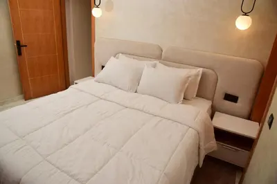 a bed with white sheets and pillows in a room at Stylish & Cozy Apartment with Modern Design in Beni Mellal