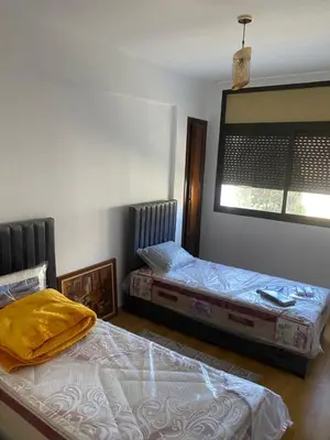 a bedroom with two beds and a mirror on the wall at Miloche home in Oulad Akkou