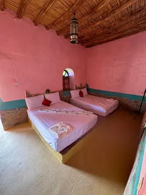 two beds in a room with pink walls at Auberge el oasis mharech in Foum Mharech