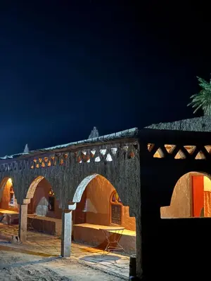 a stone building with arches at night at Auberge el oasis mharech in Foum Mharech