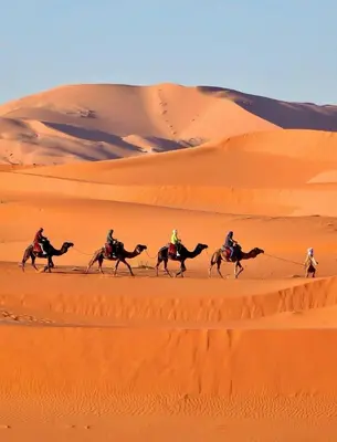 a group of people riding horses in the desert at Merzouga desert camp in Merzouga