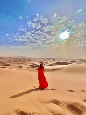 a woman in a red dress standing in the desert at Merzouga luxury tente in Merzouga