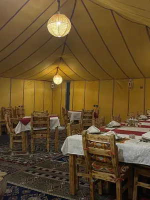 a large tent with tables and chairs in it at Merzouga luxury tente in Merzouga