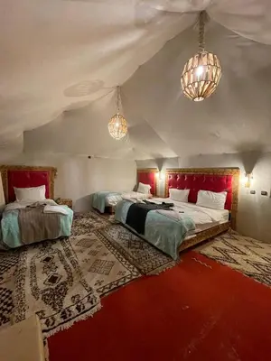 a large room with two beds and two chandeliers at Merzouga luxury tente in Merzouga