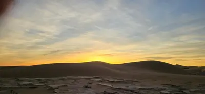 a sunset over a desert with mountains in the background at Desert feet in Mhamid