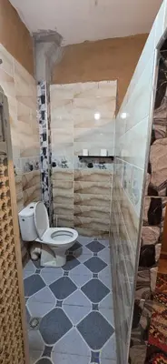 a bathroom with a toilet and a tile floor at Desert feet in Mhamid