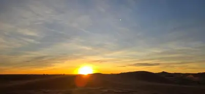 a sunset in the desert with the sun in the sky at Desert feet in Mhamid