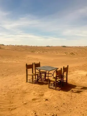 a table and chairs in the middle of the desert at Bivouac Porte du Désert in Mhamid