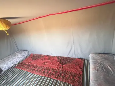 a bed in a tent with a red rug on it at Bivouac Porte du Désert in Mhamid