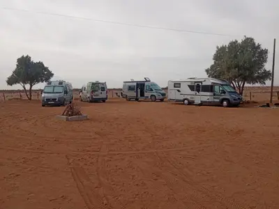 a group of vehicles parked in a dirt field at Bivouac Porte du Désert in Mhamid