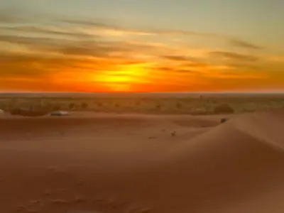 a sunset in the desert with a sand dune at Bivouac Porte du Désert in Mhamid