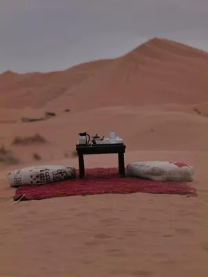 a table in the middle of a desert with two pillows at Bein Merzouga Camp in Merzouga