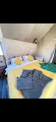a bedroom with two beds with clothes on them at Bein Merzouga Camp in Merzouga