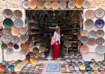 a woman standing in front of a display of pottery at Baie D'AGADIR in Oulad Akkou
