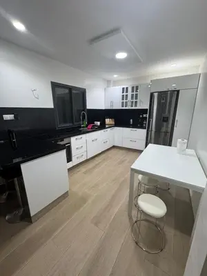 a kitchen with white cabinets and a white table and stool at Exclusive Apartment for a Perfect Getaway in Fès