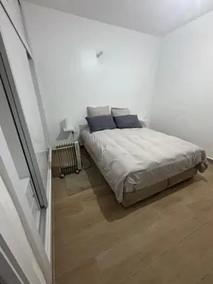 a white bedroom with a bed and a wooden floor at Exclusive Apartment for a Perfect Getaway in Fès