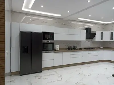 a kitchen with white cabinets and a black refrigerator at Villa de luxe avec jardin et parking privé in Beni Mellal