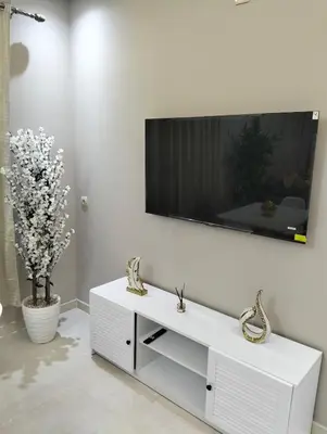 a white living room with a tv on a wall at well-equipped 2 bedroom apartment living room in Tiflet