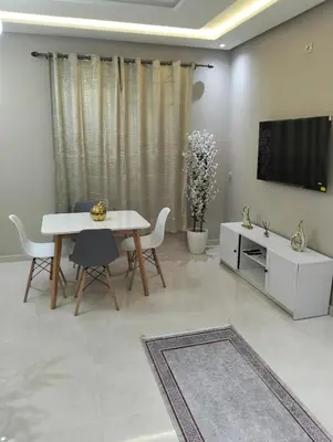 a living room with a white table and a tv at well-equipped 2 bedroom apartment living room in Tiflet