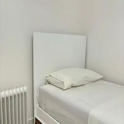 a white bedroom with a bed and a radiator at Warm & Stylish Boho Condo - 6 km to Old Medina in Fès